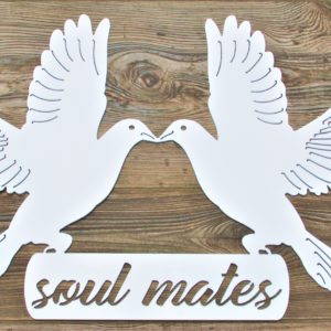 White metal sign of two doves landing on the words Soul Mates with beaks touching