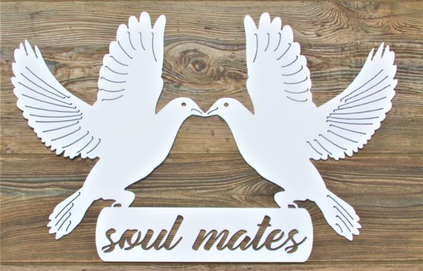 White metal sign of two doves landing on the words Soul Mates with beaks touching