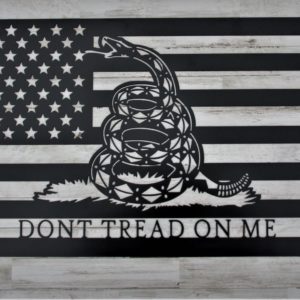 A black metal laser cut sign of an American flag with a rattlesnake in the center and the words Don't Tread on Me in all caps centered at the bottom