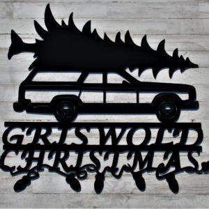 A black metal sign of a station wagon transporting a Christmas tree with the word GRISWOLD in all caps over the word CHRISTMAS in all caps below the wheels with the word Christmas intertwined with Christmas lights